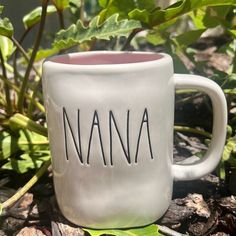 a ceramic mug with the word nanna on it sitting in front of some plants