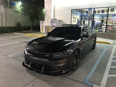 a black car parked in front of a gas station with its hood up and lights on