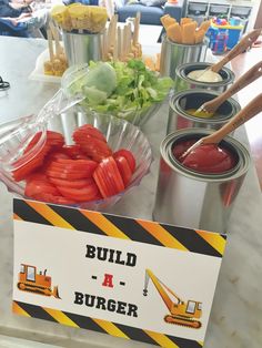 a table topped with lots of food next to containers filled with lettuce and tomatoes