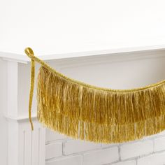 a gold tassel hanging from a fireplace mantel in front of a white brick wall