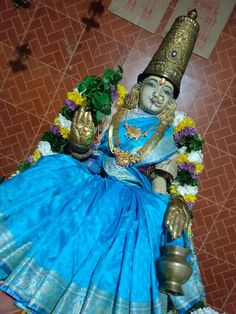 the statue is sitting on the floor with flowers around it