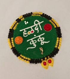 a green and yellow decoration with words written in the language of india on it's side