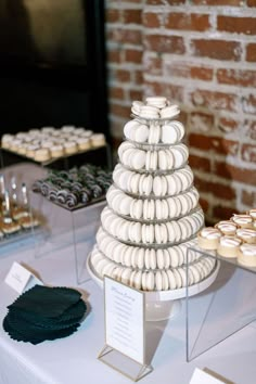 a table topped with lots of cupcakes next to a brick wall