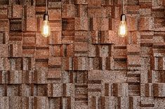 three light bulbs hanging from the ceiling in front of a wall made of brick blocks