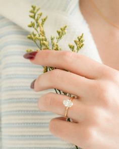 a woman wearing a gold ring with a flower in her left hand and a diamond on the middle finger