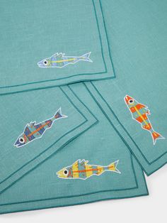 four napkins with fish embroidered on them