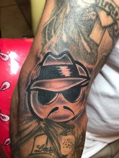 a man's arm with a tattoo on it that has an image of a person wearing sunglasses and a hat