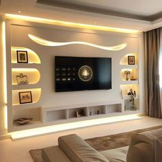 a living room with white walls and shelves on the wall, along with a large flat screen tv