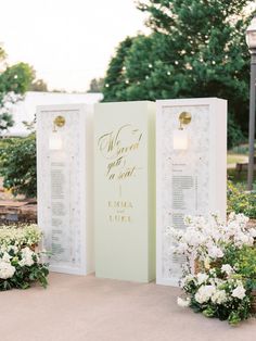 a couple of white flowers sitting on top of a table next to a tall sign