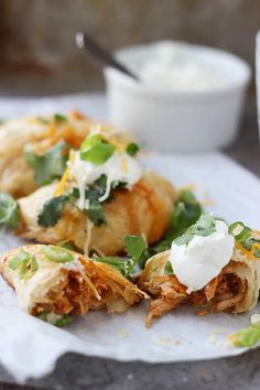 some food is sitting on a paper plate with sauce and sour cream in the background