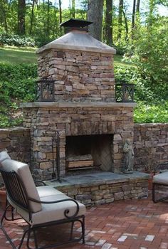 an outdoor fireplace with chairs around it