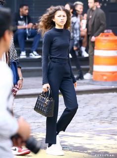 a woman in black is walking down the street