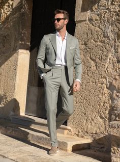 Explore a unique style with an olive/mint green suit paired with a white dress shirt, beautifully completed by tan suede loafers. A perfect ensemble for making a sophisticated yet bold statement at any event. Men’s Italian Wedding Suit, Men’s Summer Suit Wedding, Man Suit Wedding Guest, Men's Suit For Wedding, Mens Wedding Suits Summer, Italian Mens Suits, Semi Formal Mens Wedding Attire, Mens Summer Suits Wedding Guest, Wedding Suits Men Summer