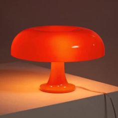 an orange table lamp sitting on top of a white counter next to a light bulb