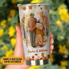 a person holding up a cup with an image of two people walking in the woods