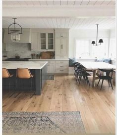 an open kitchen and dining room with white cabinets, wood floors and wooden flooring