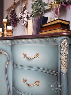 an antique dresser painted in blue with gold trimmings and flowers on the top