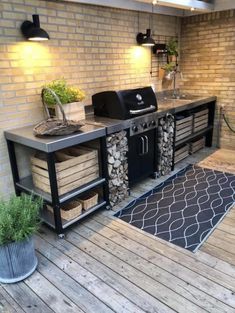 an outdoor kitchen with grill, sink and potted plants on the decking area