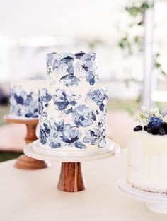 there are two cakes on the table with blue and white flowers in them, one is frosted