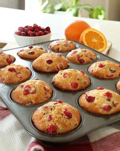 muffins with cranberries and orange slices in a pan on a table