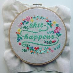 a cross - stitch hoop with the words she happens written in floral designs on it