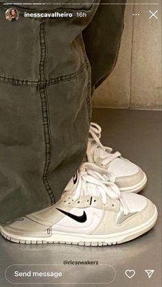 a pair of white nike shoes sitting on top of a table next to a person's leg