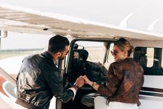 a man and woman shaking hands in front of an airplane