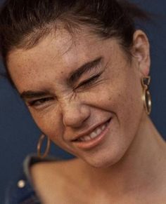 a close up of a person wearing large gold hoop earrings and smiling at the camera