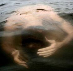 a person is swimming in the water with their hands on his head and arms extended out