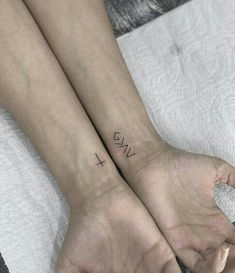 two people with matching wrist tattoos on their hands, both holding each other's hand