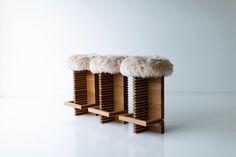 two stools with fur on them sit side by side against a white wall and floor