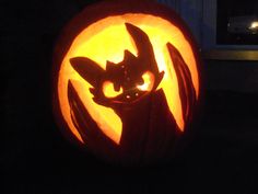 a carved pumpkin with an image of a bat on it's face in the dark