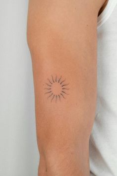 a person with a small tattoo on their arm that has a sun in the middle