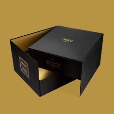 an open black box with gold foil on the inside that says, masq's