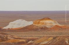 there are many hills in the desert with white and brown colors on them as well