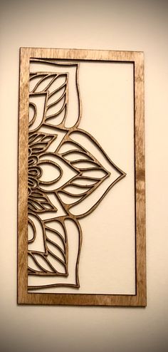 a wooden frame with an intricate design on the wall in front of a white wall