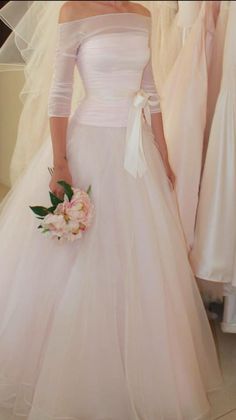 a woman in a wedding dress standing next to some dresses