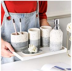 a person holding a tray with three cups and toothbrushes