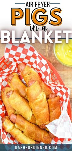 a basket filled with pigs in a blanket on top of a table next to some mustard