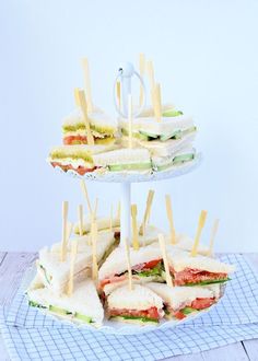 three tiered tray with sandwiches and toothpicks on it