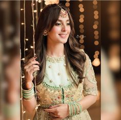 a woman in a green and gold outfit smiling at the camera with lights behind her