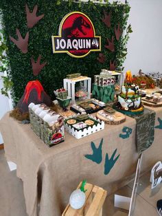 a table topped with lots of food next to a green plant covered wall in the background