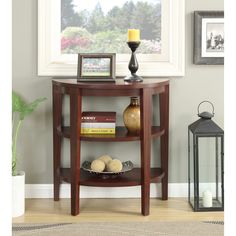 a corner table with some books on it and a vase next to it in front of a window