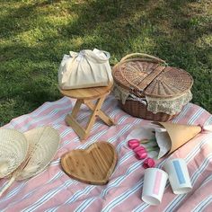 picnic items laid out on a blanket in the grass, including straw hats and baskets