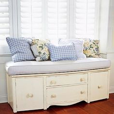 a white bench with pillows on it in front of a window that says cut the legs off an old dresser, and add a cushion