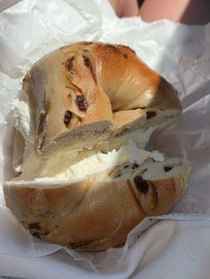 a loaf of bread with cream cheese and raisins in it sitting on wax paper