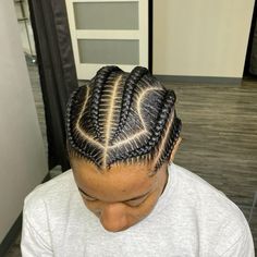 a man with cornrows sitting in front of a hair dryer wearing a white shirt