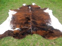 a brown and white cow skin laying on top of green grass