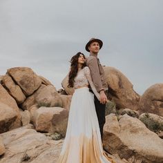 a man and woman standing next to each other on rocks