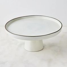 a white cake plate sitting on top of a marble countertop next to a wall